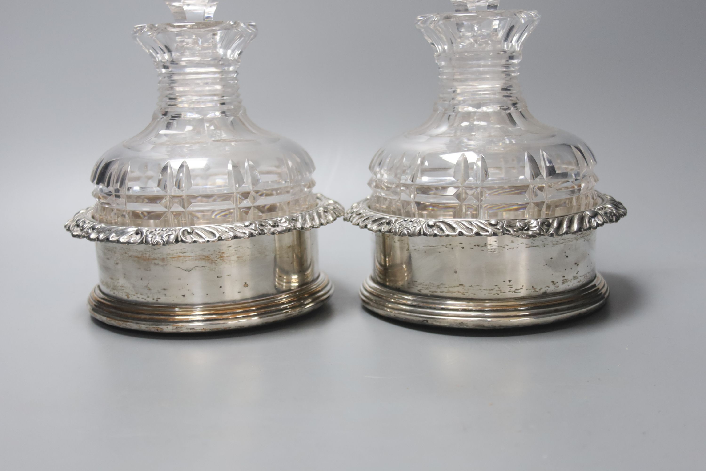 A pair of silver plated coasters with cut glass decanters. 20cm